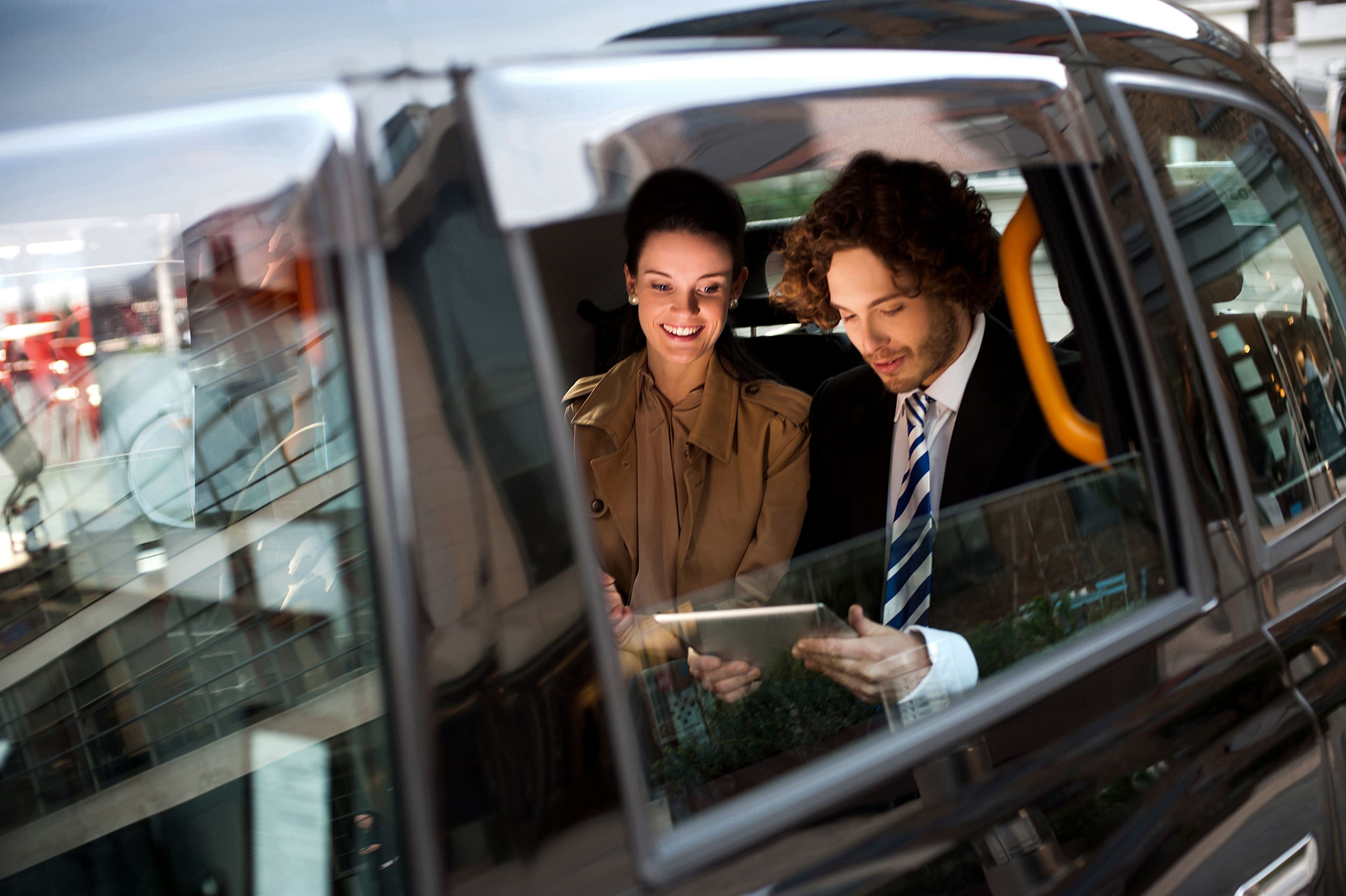 Two people getting a taxi while looking at a tablet