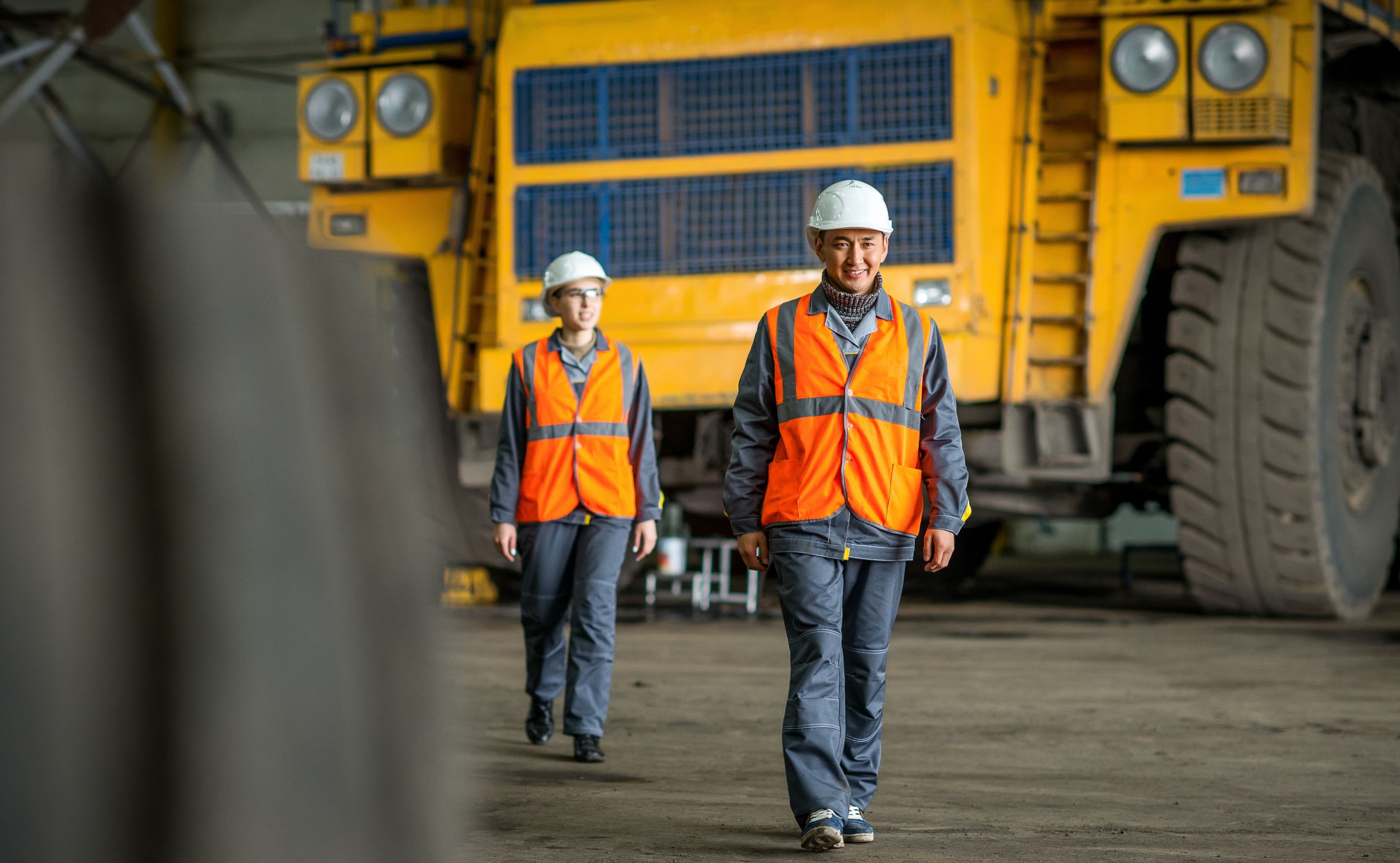 Two people walking away from a mining dump truck