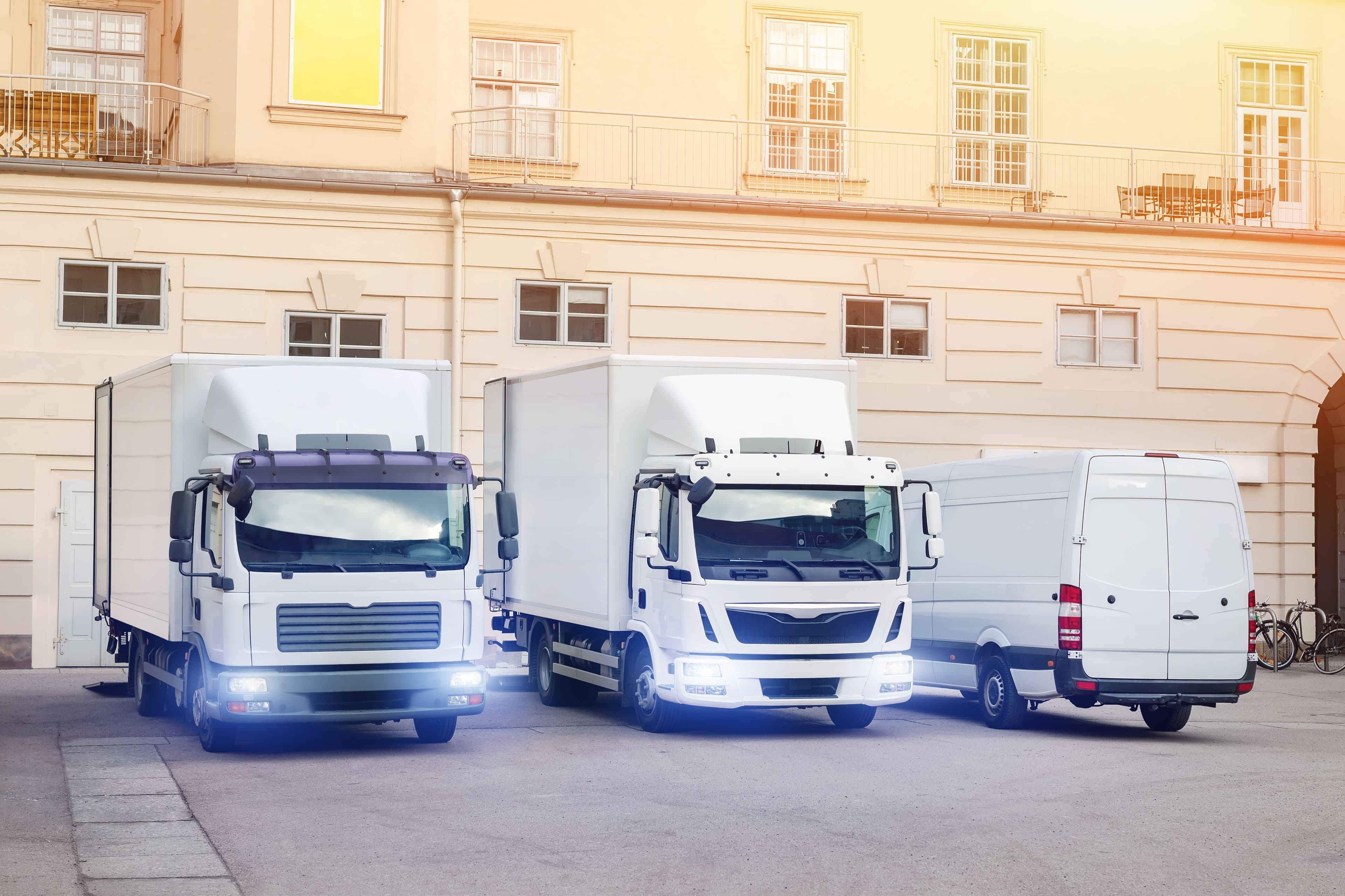 Two HGVs and a van parked outside a building
