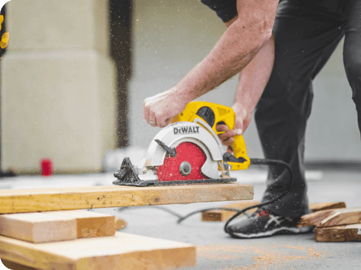 A tradesperson using a mains powered wood cutting tool