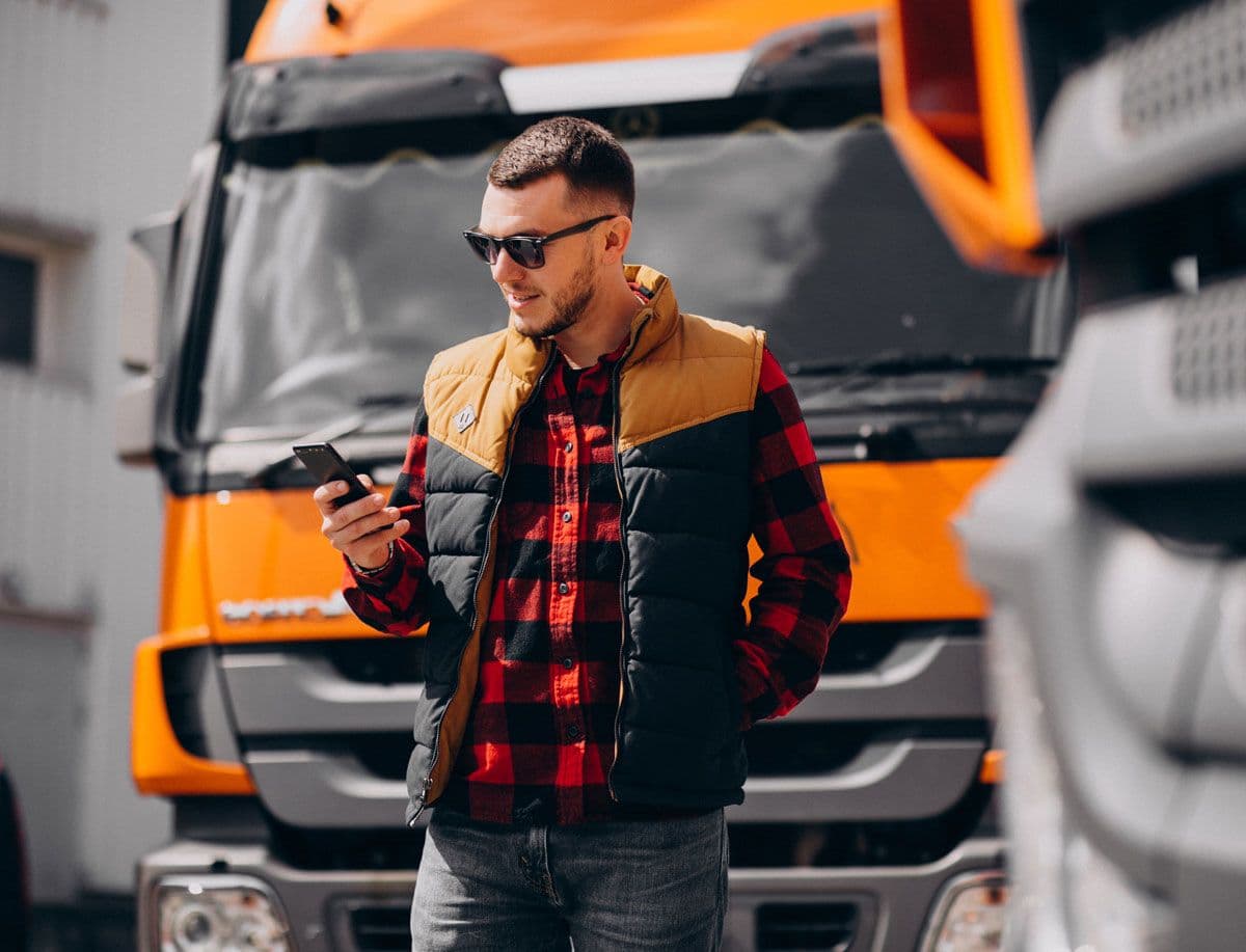 A person standing in front of a HGV while using a phone